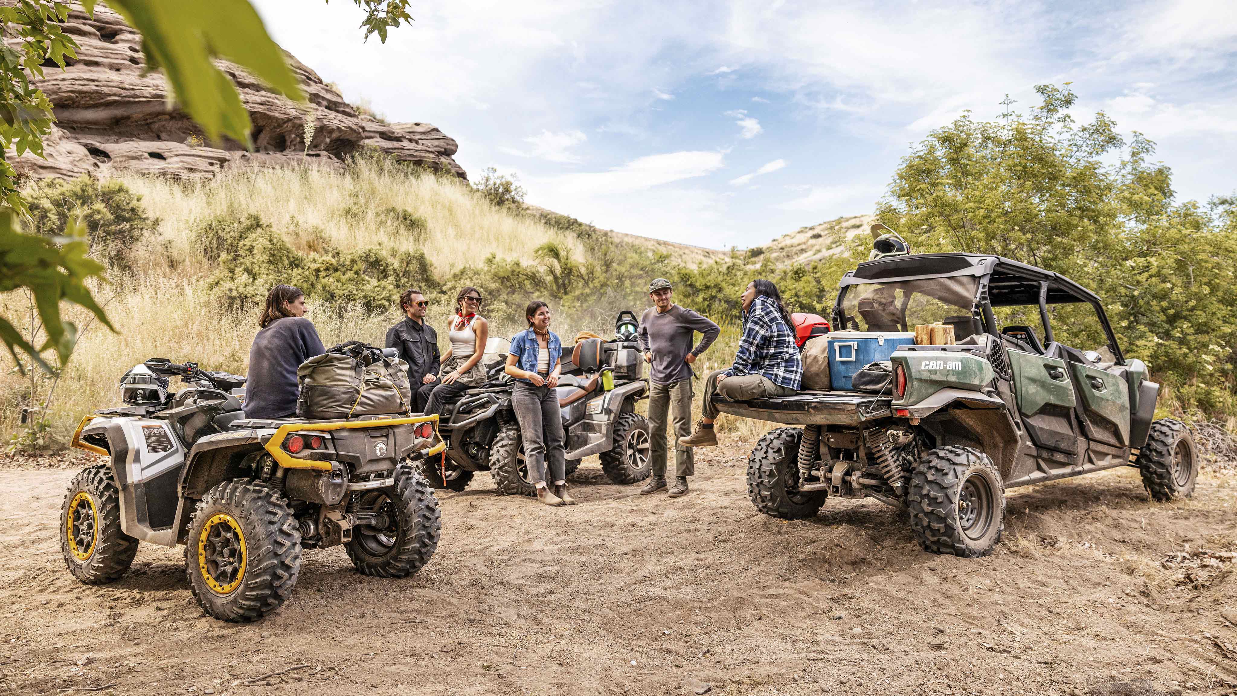 Un gruppo di motociclisti che fanno una pausa nel deserto accanto ai loro veicoli Can-Am ATV e SxS