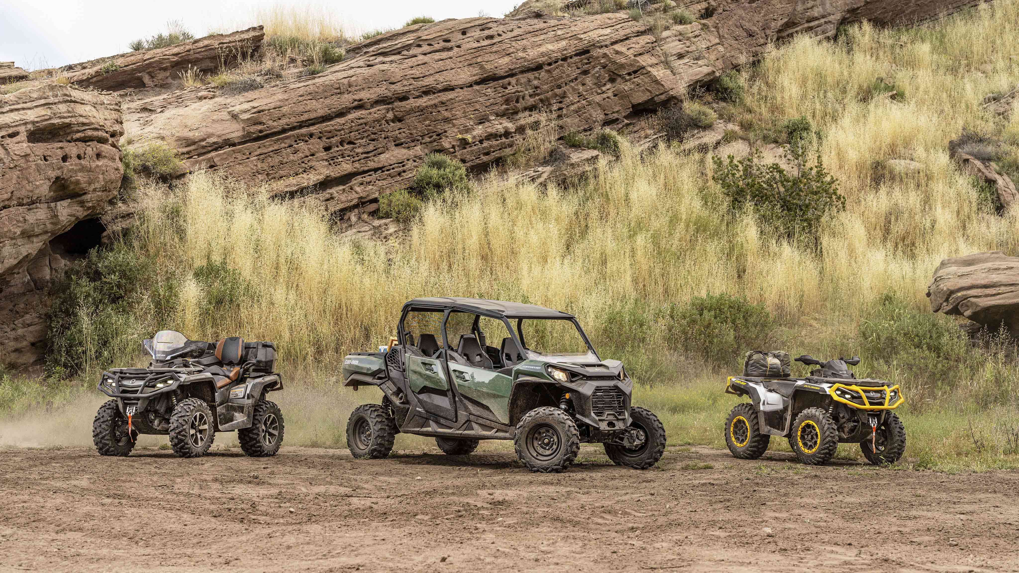 Three different Can-Am Off-Road vehicles parked on a dirt road