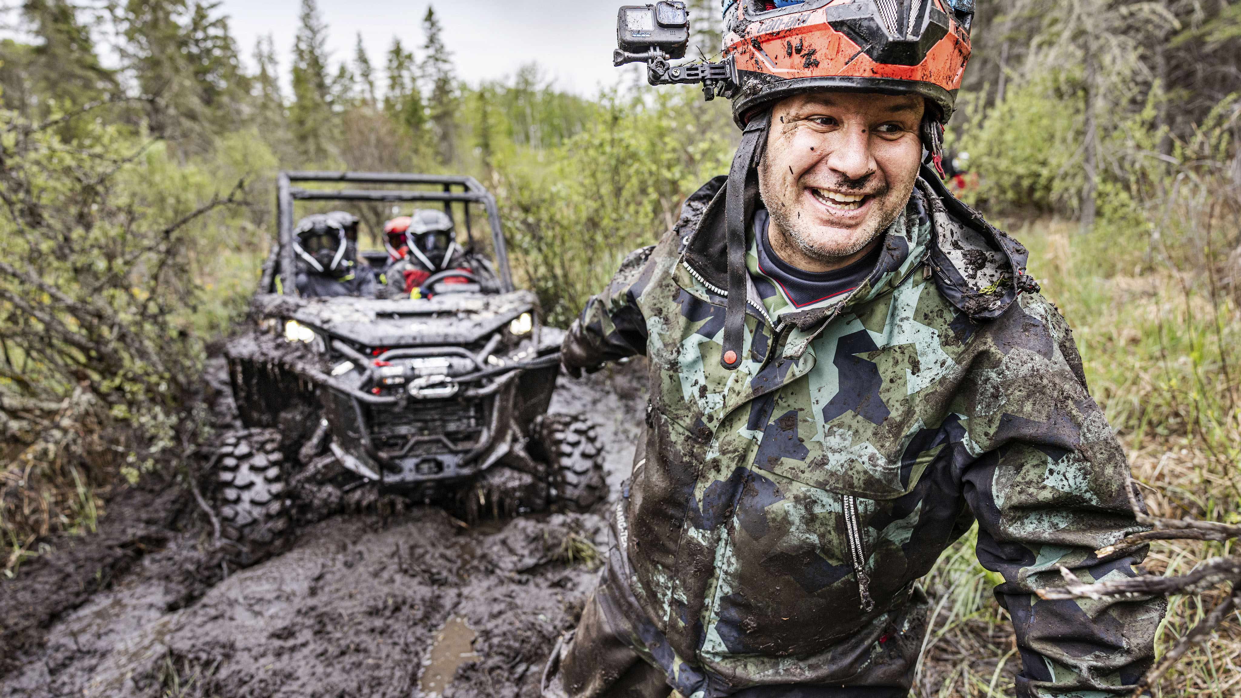 A mud-covered man pulls out the winch for a Commander X-MR stuck in mud 
