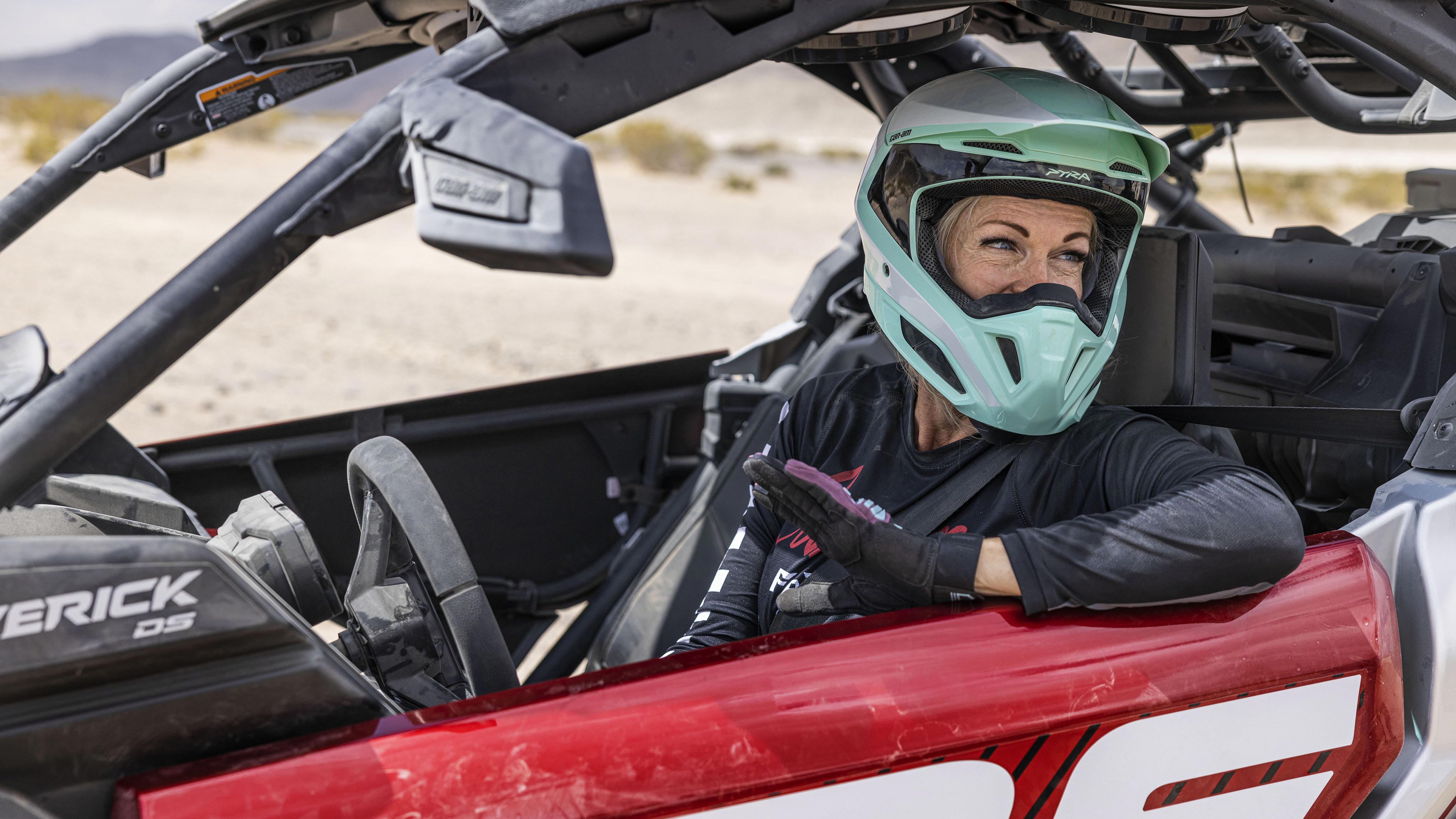 A woman wearing a mint green helmet in the drivers seat of a Maverick X3