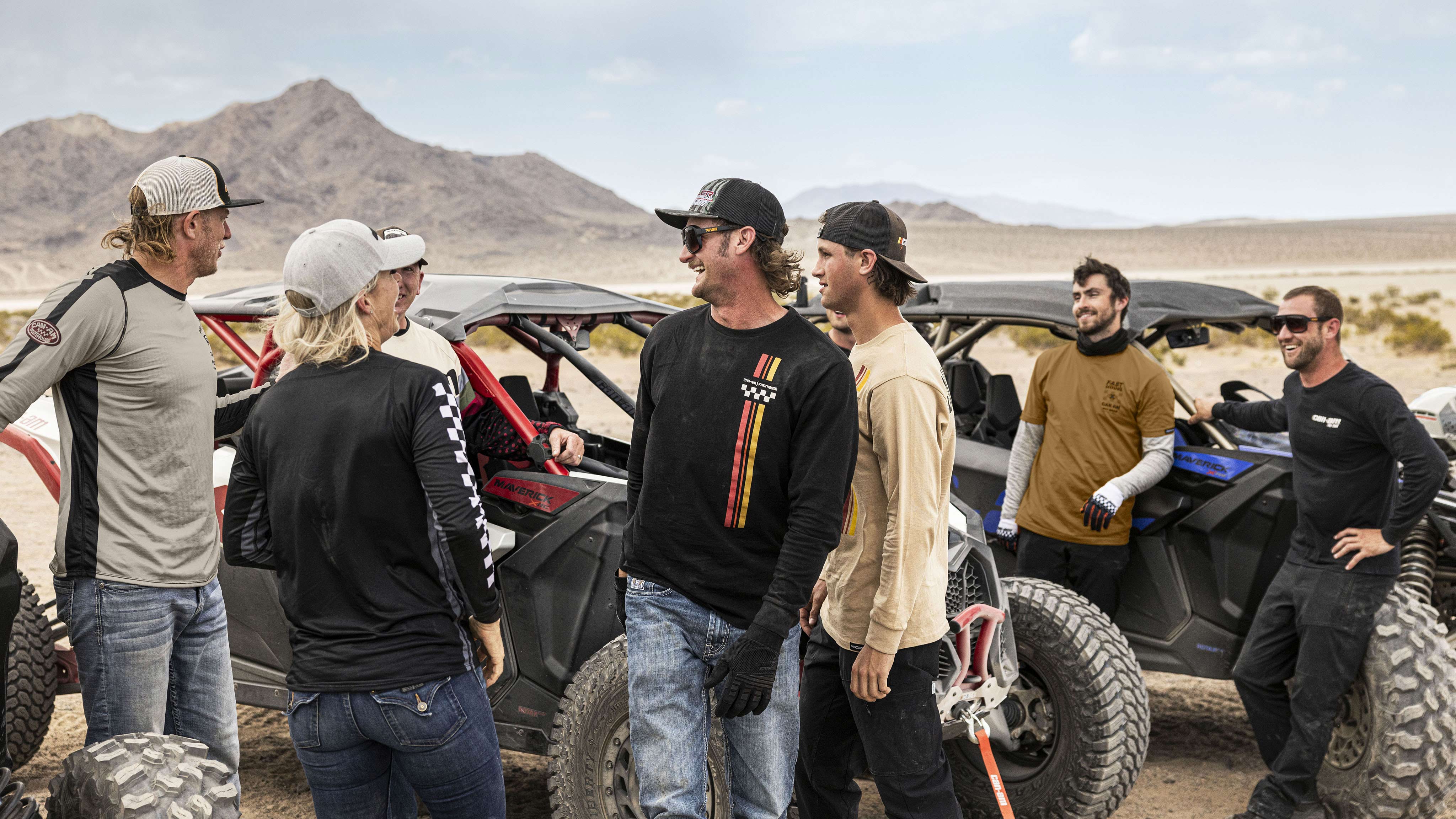 A group of 8 friends standing around 2 Maverick X3's laughing 