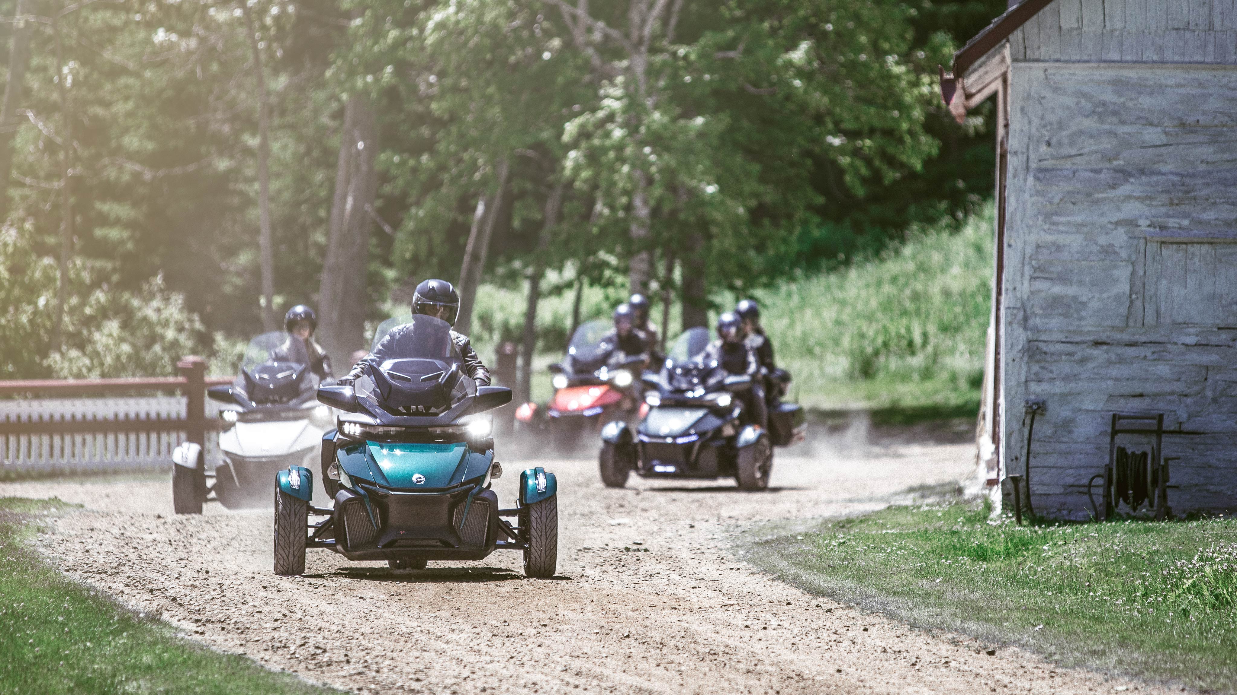 A group of riders navigating their Can-Am vehicles around the corner of a dirt road