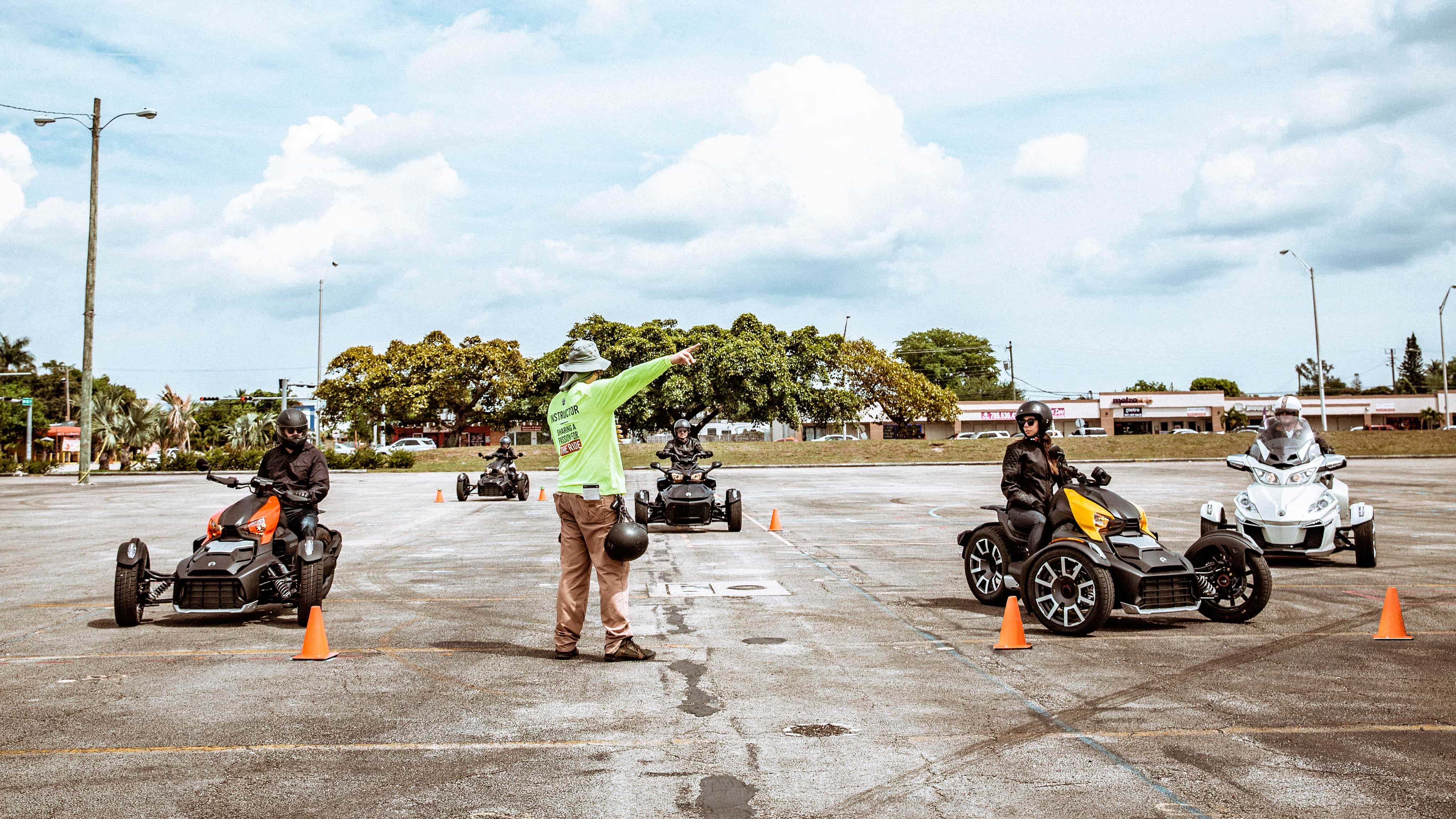 Instruktör som ger signaler till en grupp förare på 3-hjuliga motorcyklar.