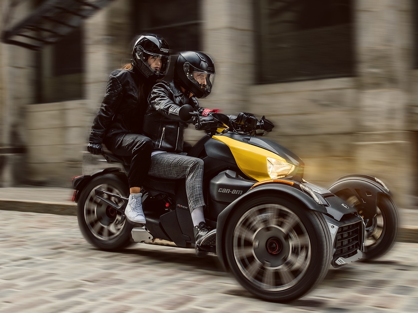 Man on a yellow Can-Am Ryker in the city with female passenger