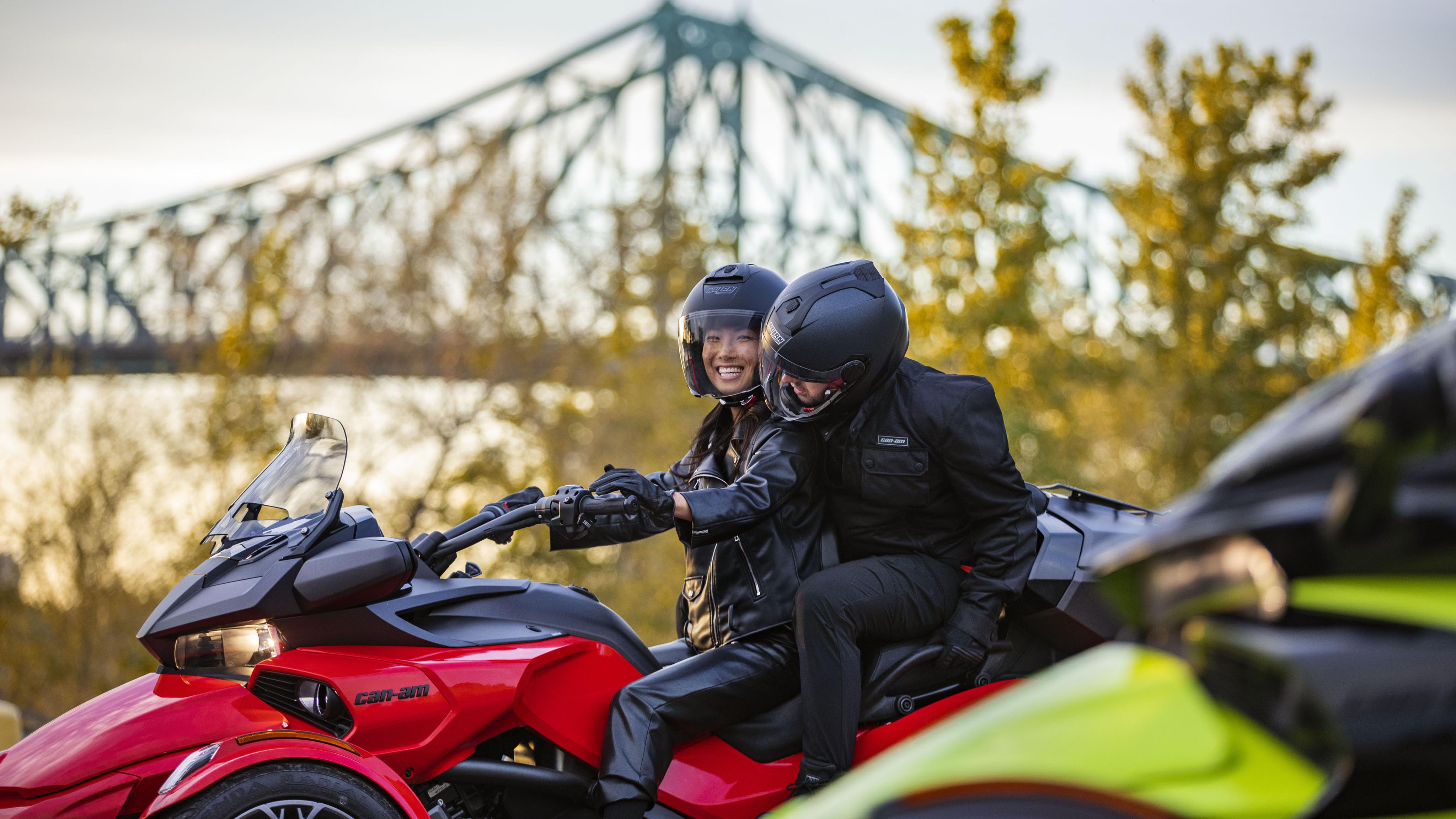Couple sitting on a Can-Am Spyder F3 next to a bridge
