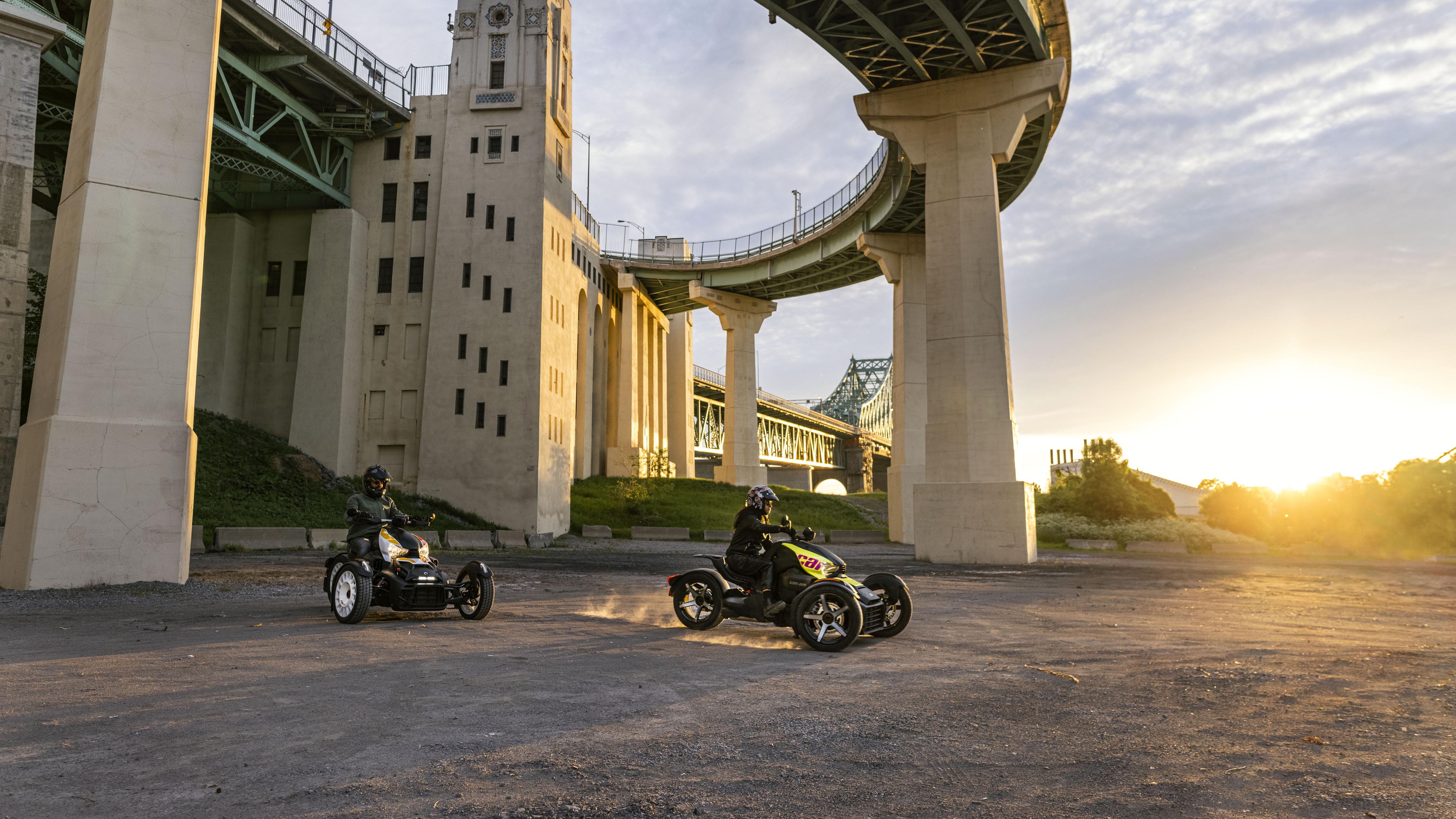 Two Can-Am Ryker vehicles under a viaduct