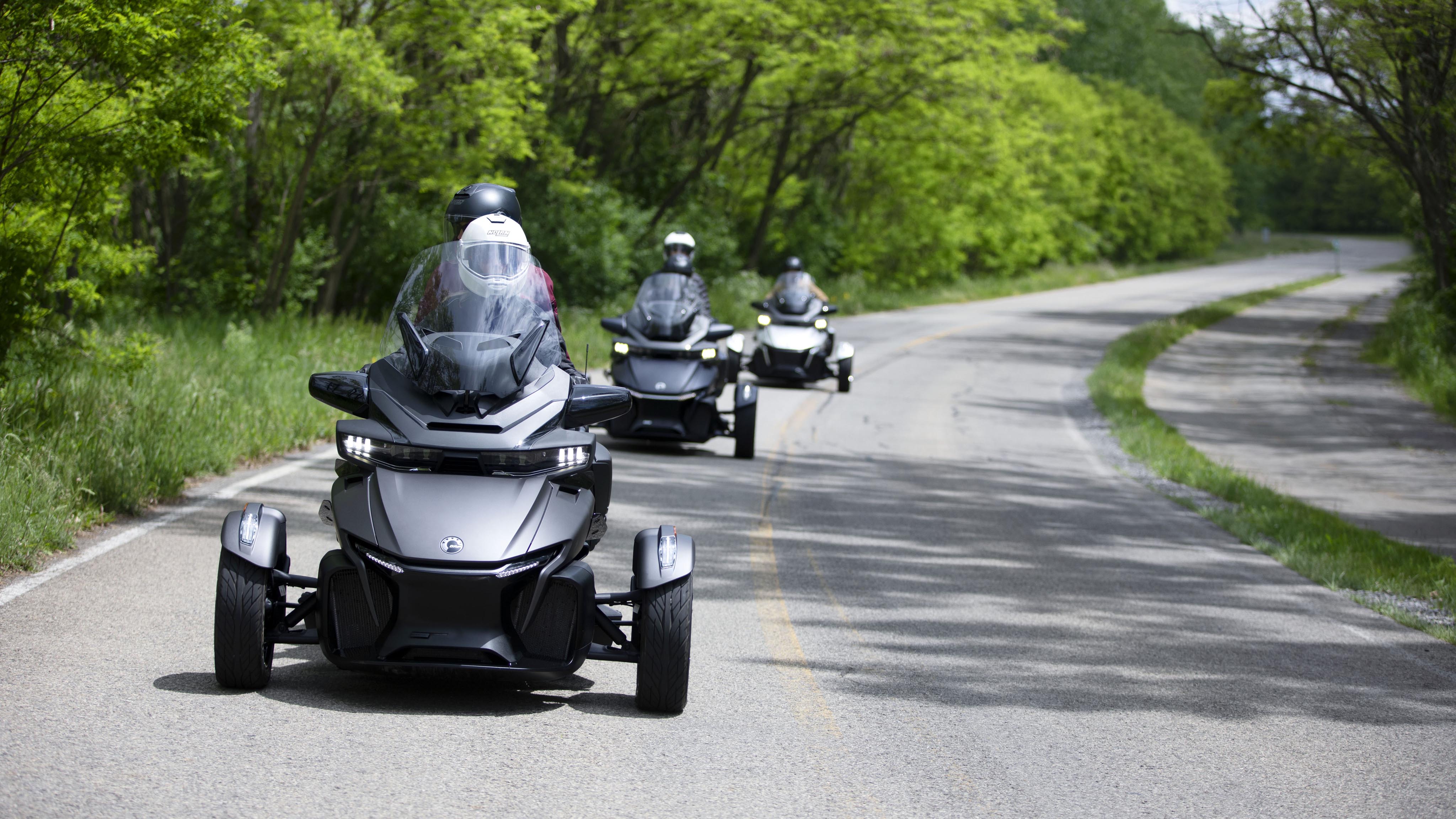 People riding Can-Am vehicles on a road