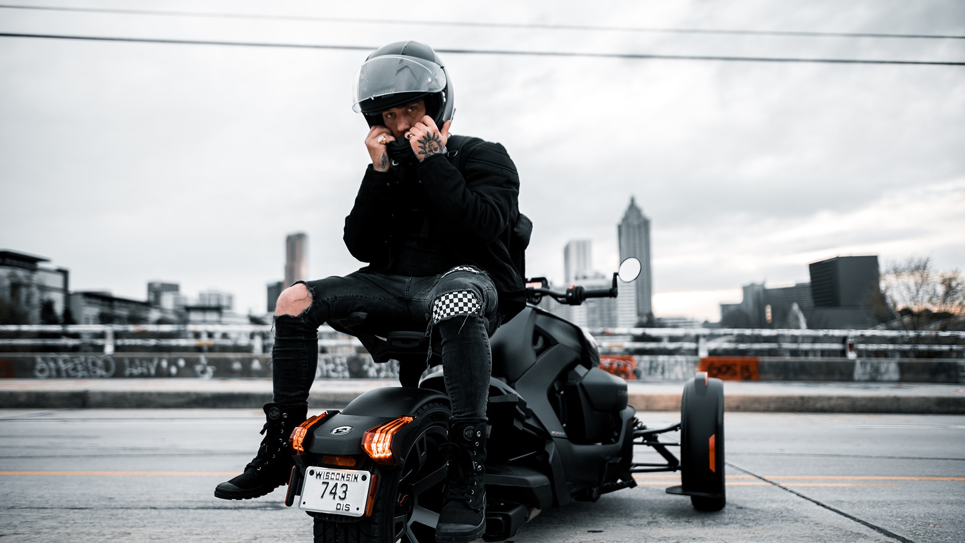 Can-Am On-Road ambassador Creative Ryan sitting on this 3-wheel motorcycle about to remove his helmet
