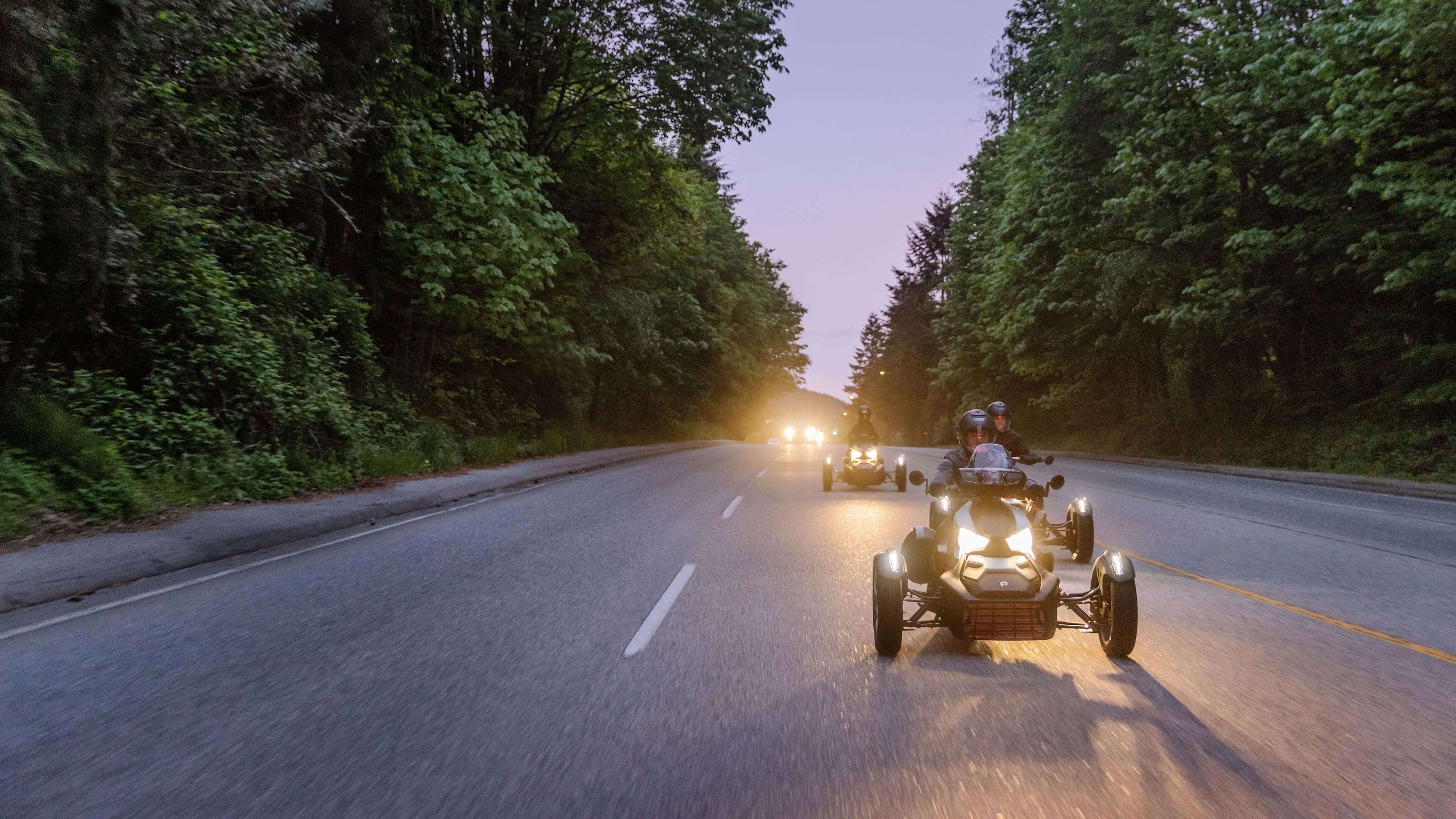 A rider on his 2026 Can-Am 3-wheeler driving on a road with trees on both sides