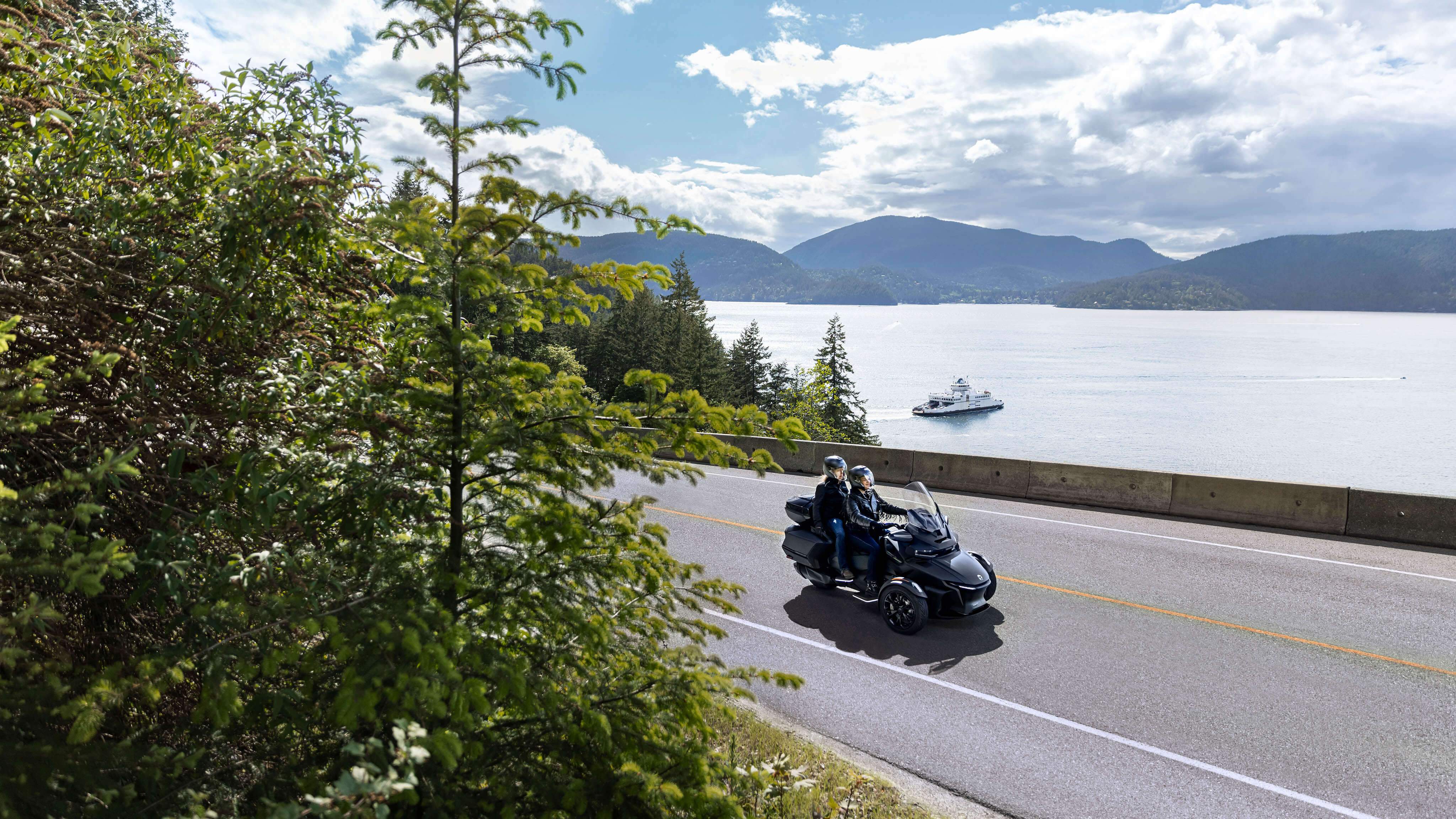 A driver and passenger on a 2023 Can-Am Spyder RT on a scenic road