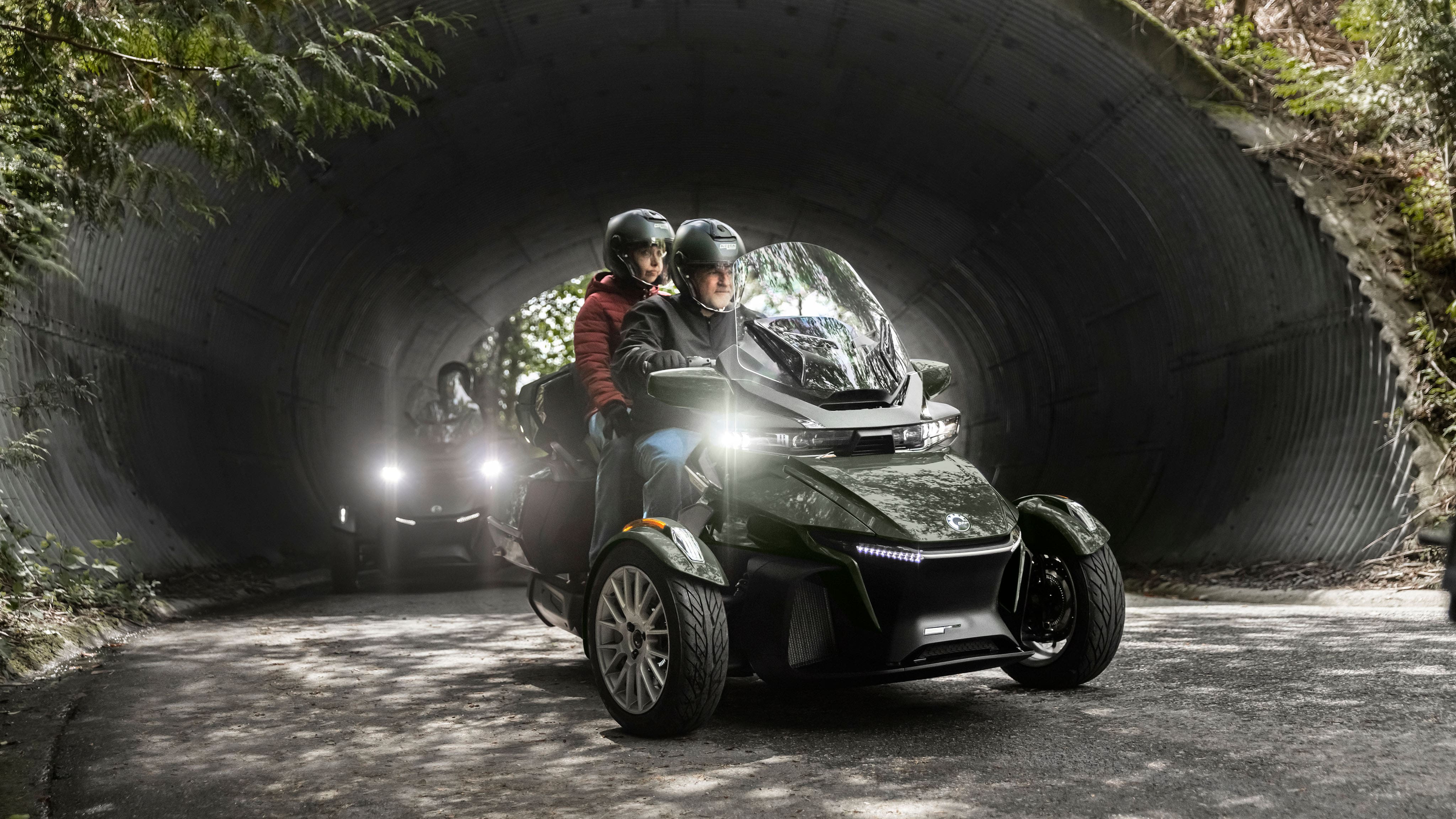 A driver and passenger on a 2023 Can-Am Spyder RT on a scenic road