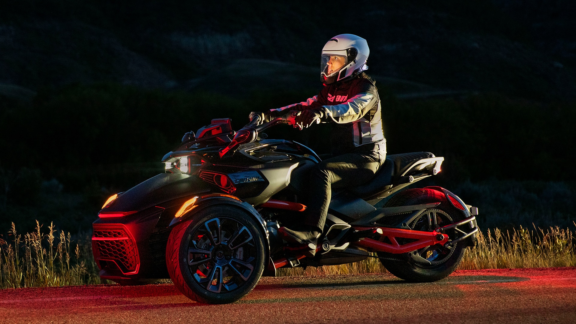 Rider sitting on a Can-Am Spyder F3 3-wheel vehicle at night