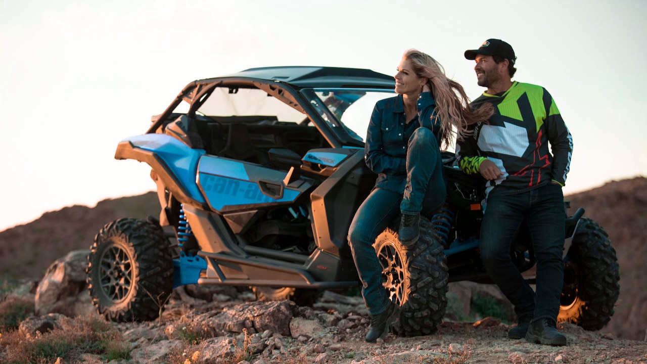 A couple relaxing next to a Can-Am Off-Road vehicle