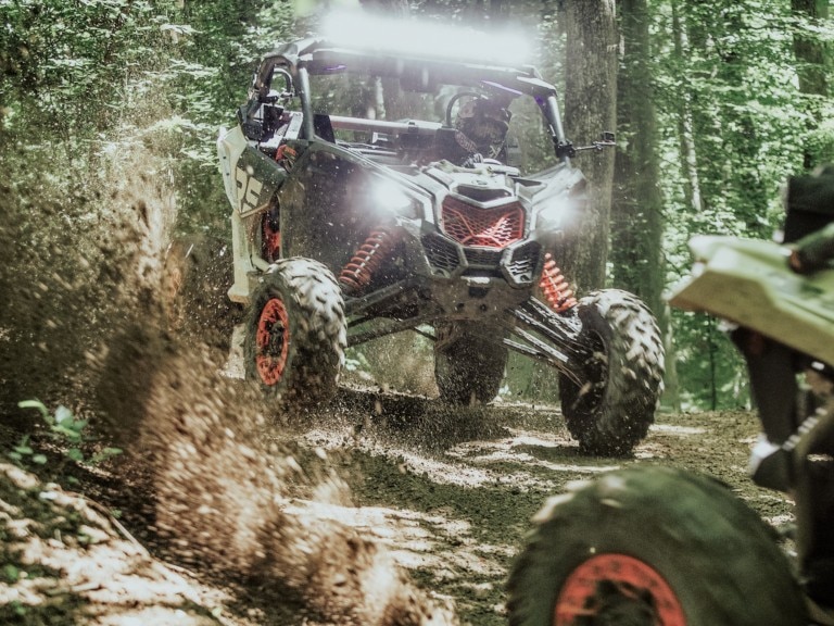 Two Can-Am Off-Road vehicles riding in the woods