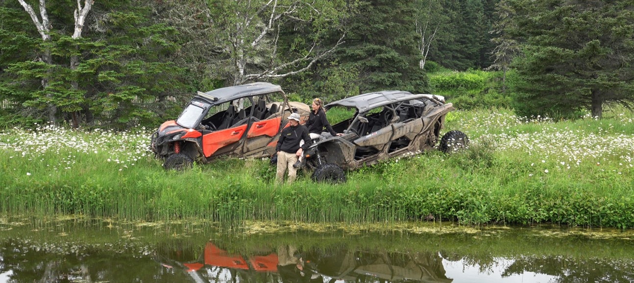 Two side-by-side vehicles parked in front of a lake